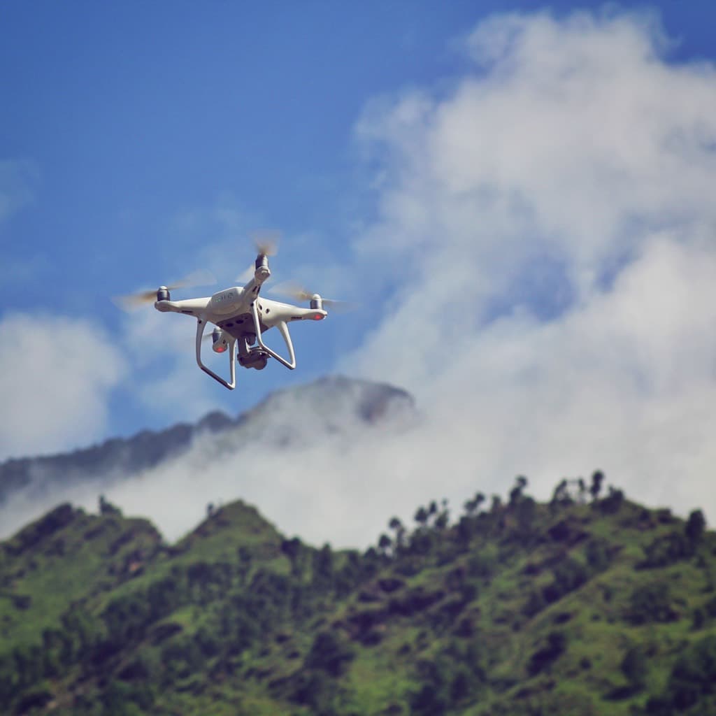 雲がかかる山の稜線を飛行する無人航空機